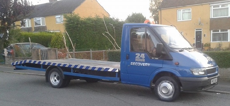 wide angled shot shwing a blue flatbed recovery truck